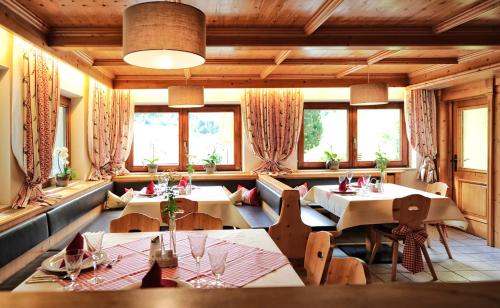un ristorante con tavoli, sedie e finestre di Gletscher-Landhaus Brunnenkogel a Sankt Leonhard im Pitztal