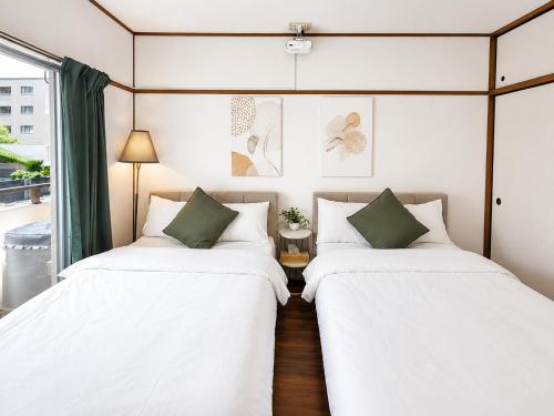 two beds in a room with white sheets and green pillows at 徳島駅徒歩10分 公園前 Netflix DiDi Base 203 in Tokushima
