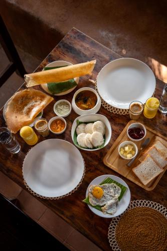 a wooden table with plates of food on it at The Mudhouse Marayoor in Munnar