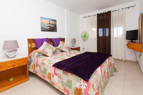 a bedroom with a bed and a television in it at Ap Esmeralda in Caleta De Fuste