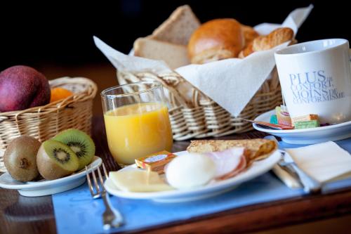 a breakfast table with a basket of bread and orange juice at Kyriad Paris Ouest - Bezons La Défense in Bezons