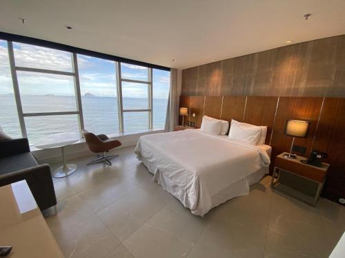 a bedroom with a large white bed and large windows at Hotel Nacional Rio in Rio de Janeiro