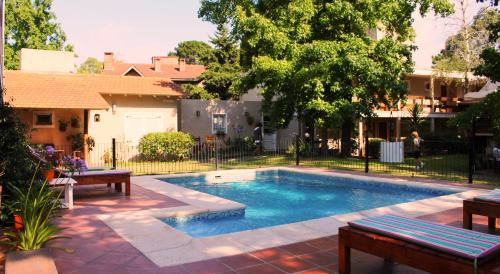 una piscina con 2 bancos junto a una casa en El Cortijo en Pinamar