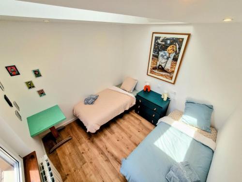 a bedroom with two beds and a painting on the wall at Chez Simone in Ploemeur