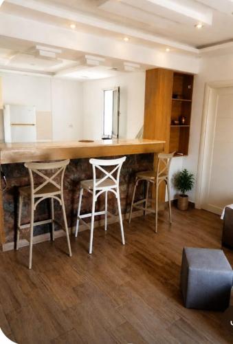 a kitchen with a bar with four stools at Résidence Nour in Monastir