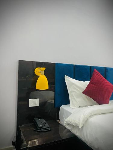 a bed with a side table with a phone on it at Sky Hotel in Lucknow