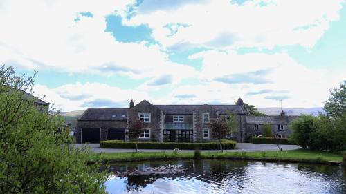 a house with a lake in front of it at Estatesmen Lodge, Hillside Farm in Kirkby Stephen
