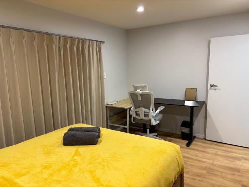 a bedroom with a yellow bed and a desk at Ke's home in Wellington