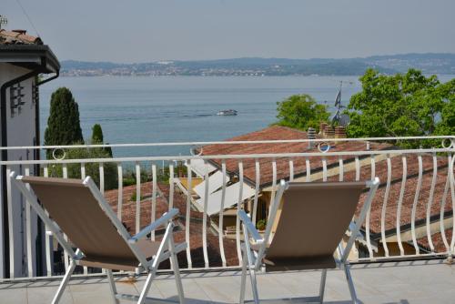 two chairs on a balcony with a view of the water at Hotel Luna in Sirmione