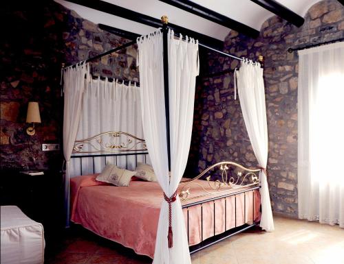 - une chambre avec un lit à baldaquin et des rideaux dans l'établissement Hotel Restaurante Verdia, à Sueras