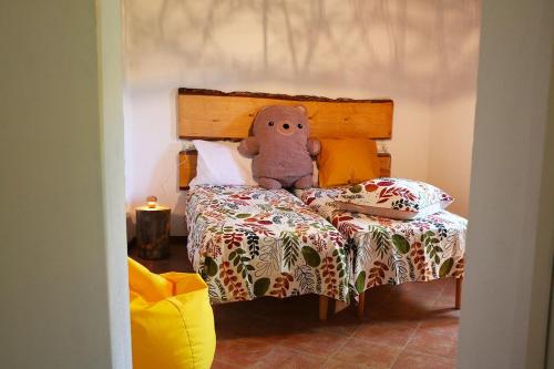 a stuffed teddy bear sitting on a bed at Quercus La Baita in La Verna