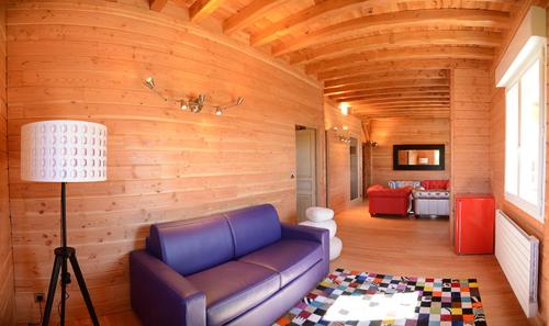 a living room with a blue couch in a wooden room at Domaine du Mont Monnet - Chambre d'hôtes & Gîte in Longes