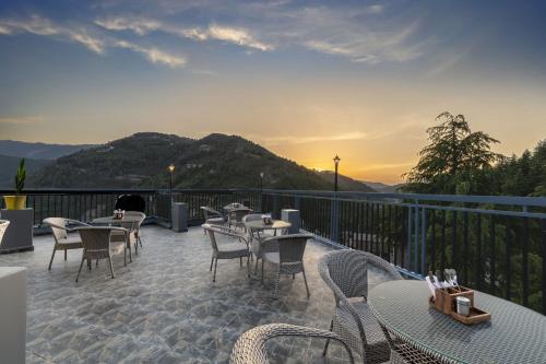 a patio with tables and chairs on a balcony at Echor Alpine Meadows Khajjiar Dalhousie in Khajjiar 