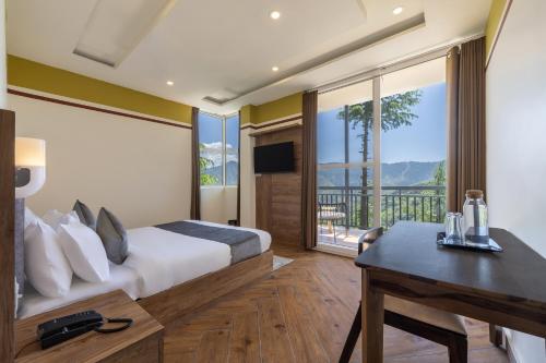 a bedroom with a bed and a desk and a balcony at Echor Alpine Meadows Khajjiar Dalhousie in Khajjiar 