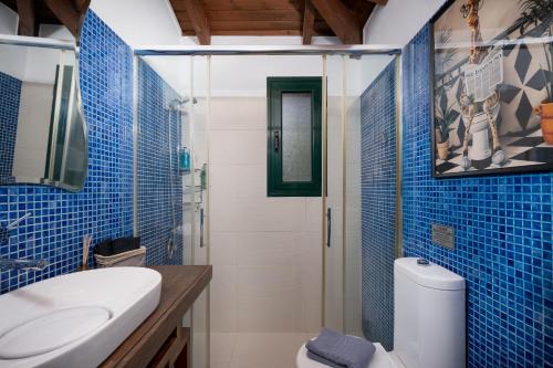 a blue tiled bathroom with a toilet and a sink at Ever Eden Residence by A&D Properties in Porto Rafti