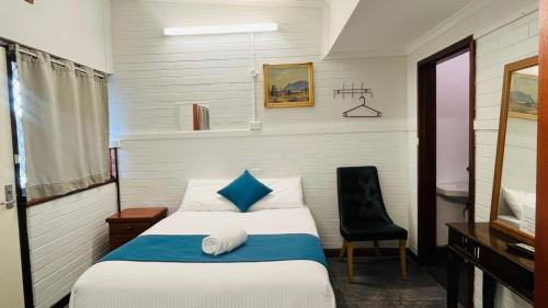 a small bedroom with a bed and a chair at Railway Lodge Motel in Taree