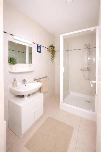 a white bathroom with a sink and a shower at Résidence les 4 Horizons in Cerbère