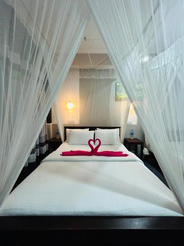 a white bed with a red ribbon on it at The Bliss Homestay in Ella