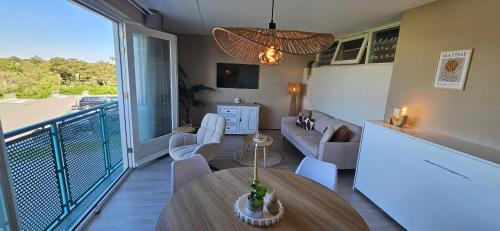 a living room with a table and a balcony at Bon Diaz at Sea in Julianadorp