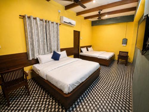 two beds in a room with yellow walls at Hotel Rudra Ganga View Near Temple in Varanasi