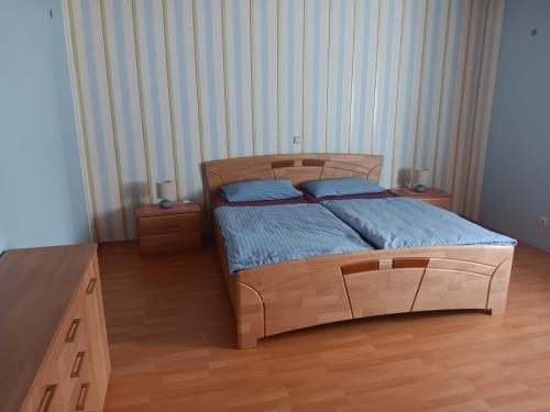 a bedroom with a bed with blue sheets and two night stands at Hunsrücktraum in Mittelstrimmig
