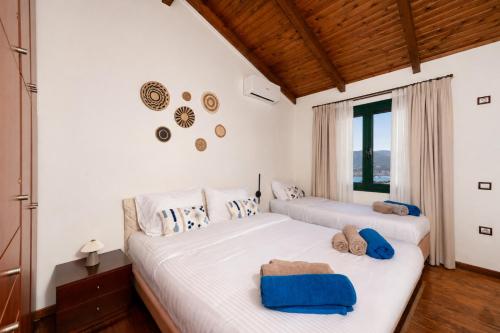 two beds in a bedroom with white walls and wooden floors at Ever Eden Residence by A&D Properties in Porto Rafti