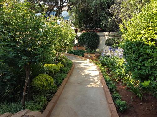a walkway in a garden with plants and trees at Homestay Travel Guest House in Roodepoort