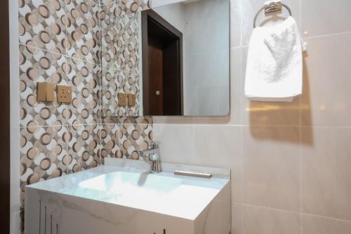 a bathroom with a white sink and a mirror at Belmar Inn Apartments in Jazan