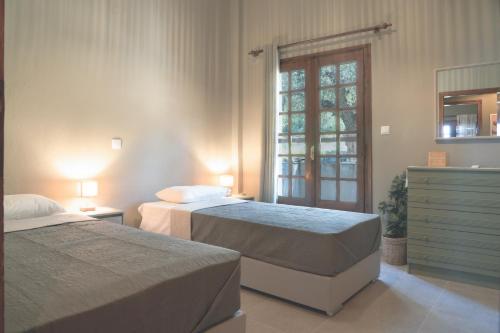 a bedroom with two beds and a dresser and a window at Aria Seaview Villa in Vourvourou