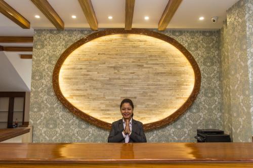 a man sitting at a desk in front of a wall at Hotel White Pearl in Pokhara