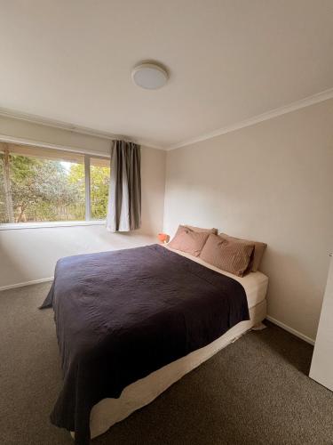 a bedroom with a large bed and a window at The Bach at One Tree Point in One Tree Point