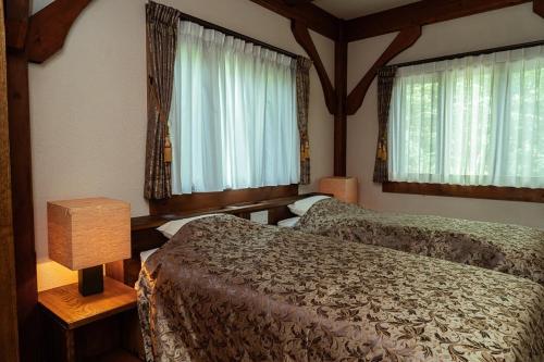 a bedroom with two beds and two windows at 山あいの静かなログハウス Quiet Mountain Log House with Indoor Hot Spring Bath in Gujo