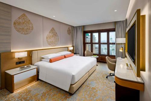 a hotel room with a bed and a desk and a television at Makkah Hotel in Mecca