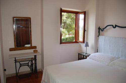 um quarto com uma cama branca e um espelho em Casa dell'Oleandro em Torre Faro