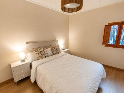 a bedroom with a white bed with two lamps on it at Casa río de Bolbaite in Bolbaite