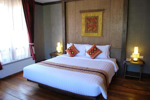 a bedroom with a large white bed with two pillows at Haven Resort Paro in Paro