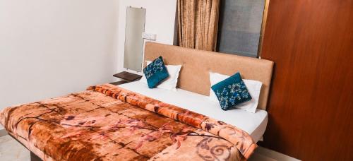 a bedroom with a large bed with blue pillows at Grand Ayushmaan - Best Hotel in Jabalpur in Jabalpur