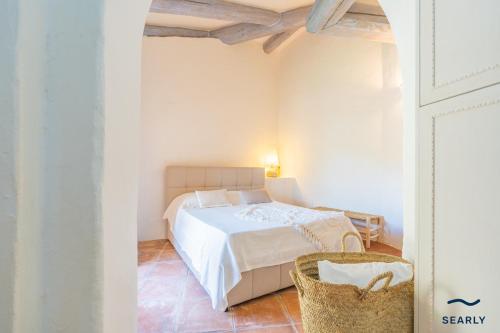a white bedroom with a bed and a chair at Villa Domo Mea - By Searly in Porto Cervo