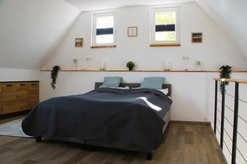 a bedroom with a bed and two windows at Ferienwohnung Am Sieler in Südbrookmerland