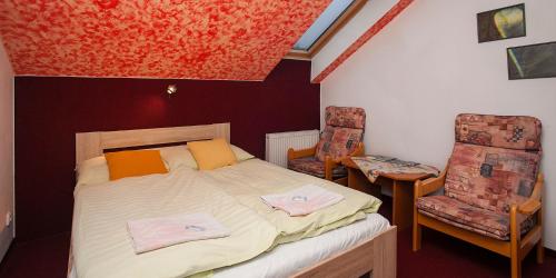 a small bedroom with a bed and two chairs at Penzion Měšťanský Dům in Svoboda nad Úpou