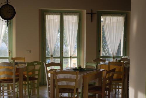 a dining room with tables and chairs and windows at Le Maraclà Country House in Iesi