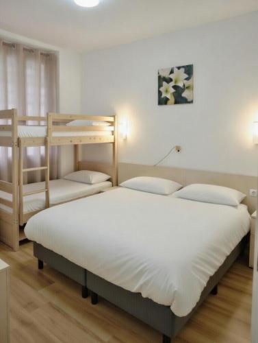 two beds in a room with two bunk beds at Hôtel Croix des Nordistes in Lourdes
