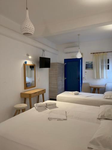 a bedroom with two beds and a table and a mirror at Romantika in Platis Gialos