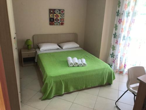 a bedroom with a green bed with two rolled towels at Theodora villas Portaria beach 2 in Paralia Dionysiou