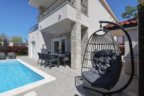 a swing next to a house with a swimming pool at Casa Coral in Zadar