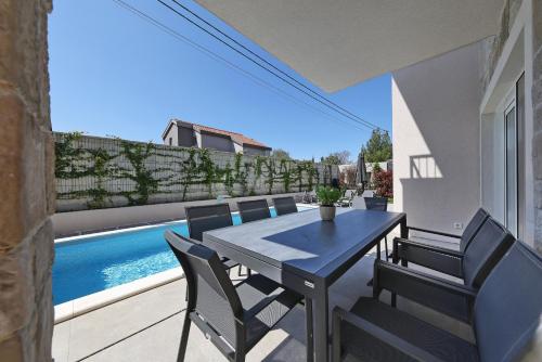 a dining table and chairs on a patio with a pool at Casa Coral in Zadar