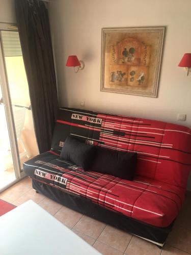 a red couch sitting in a living room at Location appartement proche Saint Tropez in Roquebrune-sur-Argens
