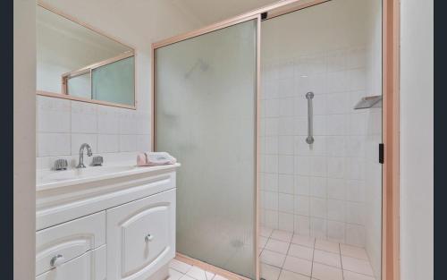 a white bathroom with a shower and a sink at Bungo Beach Shack in Eden