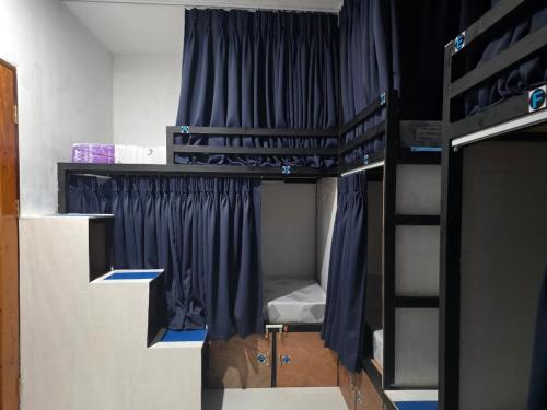 a room with two bunk beds with blue curtains at 7641guesthouse in Basdiot