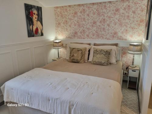 a bedroom with a white bed with pink wallpaper at L'escapade des Cévennes in Rousson